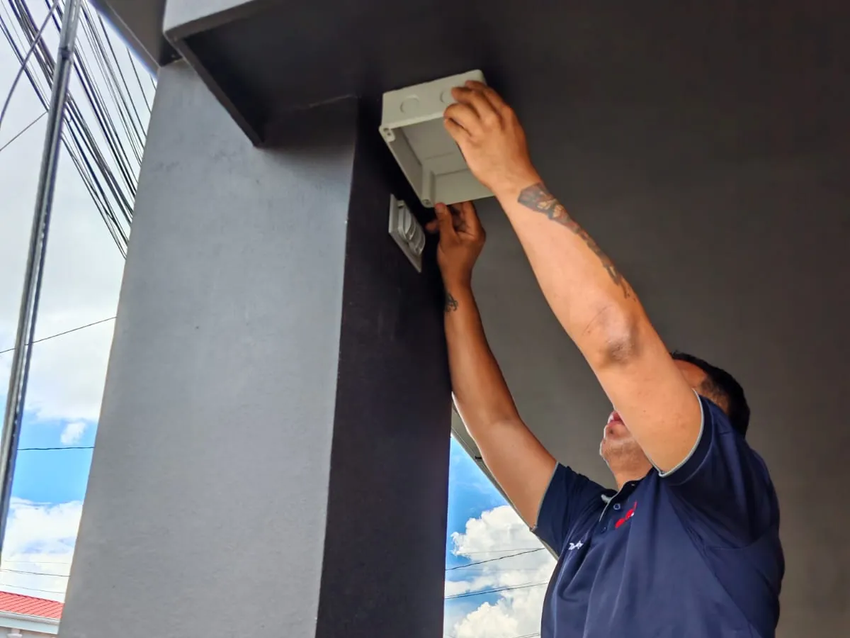 Técnico instalando equipo de seguridad en la fachada de una casa en Alajuela